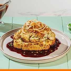 Cauliflower bistek on a gray plate with sauce on the side. Cauliflower bistek on a gray plate with sauce on the side.