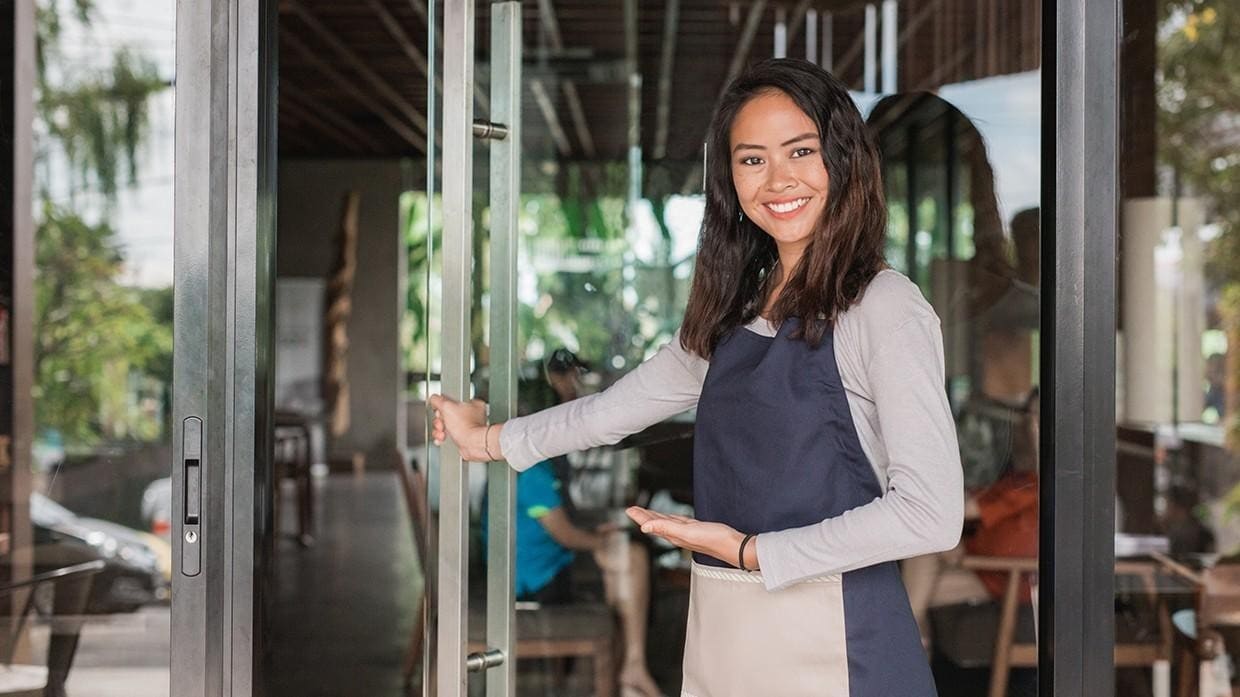 A smiling waitress opening the door and welcoming guests. A smiling waitress opening the door and welcoming guests.