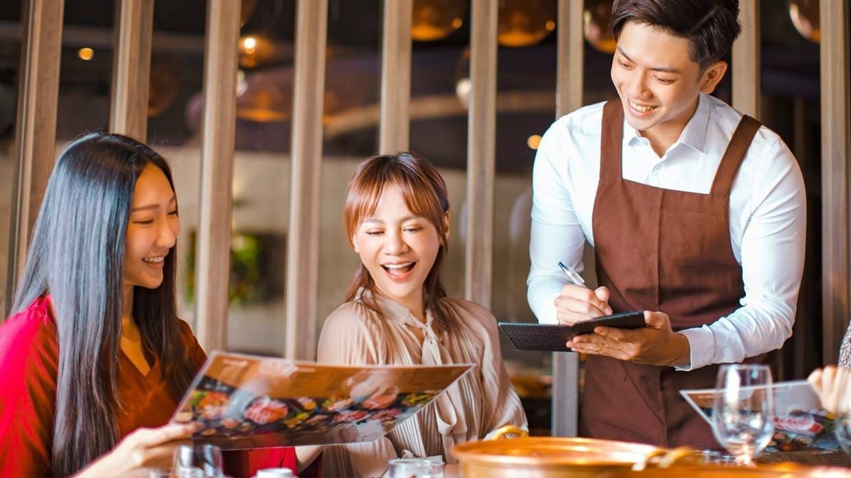 A waiter taking orders with a pen and order pad. A waiter taking orders with a pen and order pad.