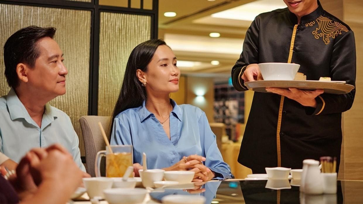 A waiter serving soup to a couple. A waiter serving soup to a couple.