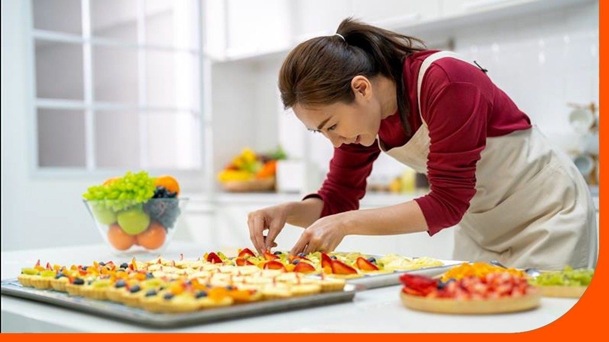 A woman adding toppings to desserts in a white kitchen. A woman adding toppings to desserts in a white kitchen.